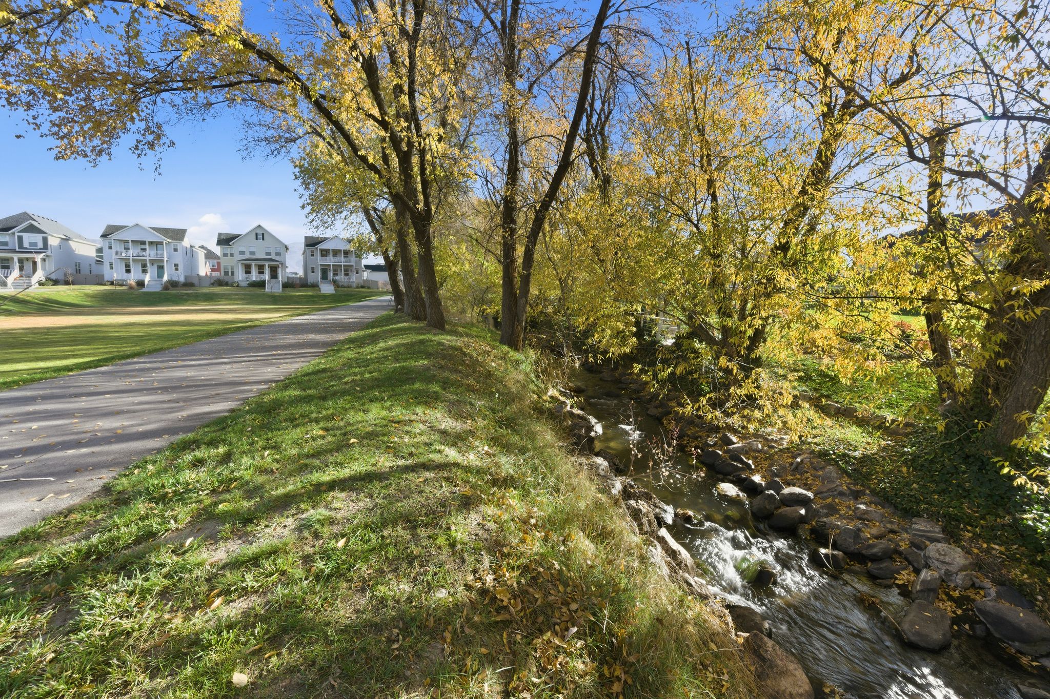 Natural creek with flowing water, bordered by mature trees with golden foliage