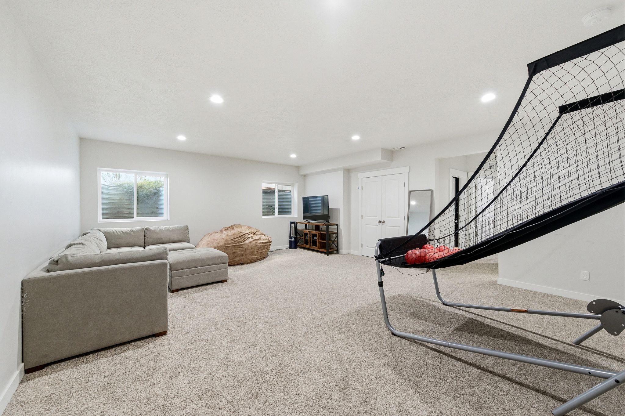 Spacious carpeted room featuring recessed lighting, white walls, and multiple windows with white blinds