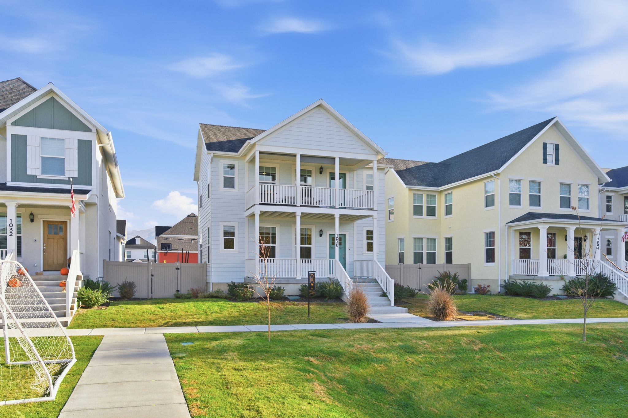 Two-story residence featuring a white facade with dual balconies and a turquoise entry door