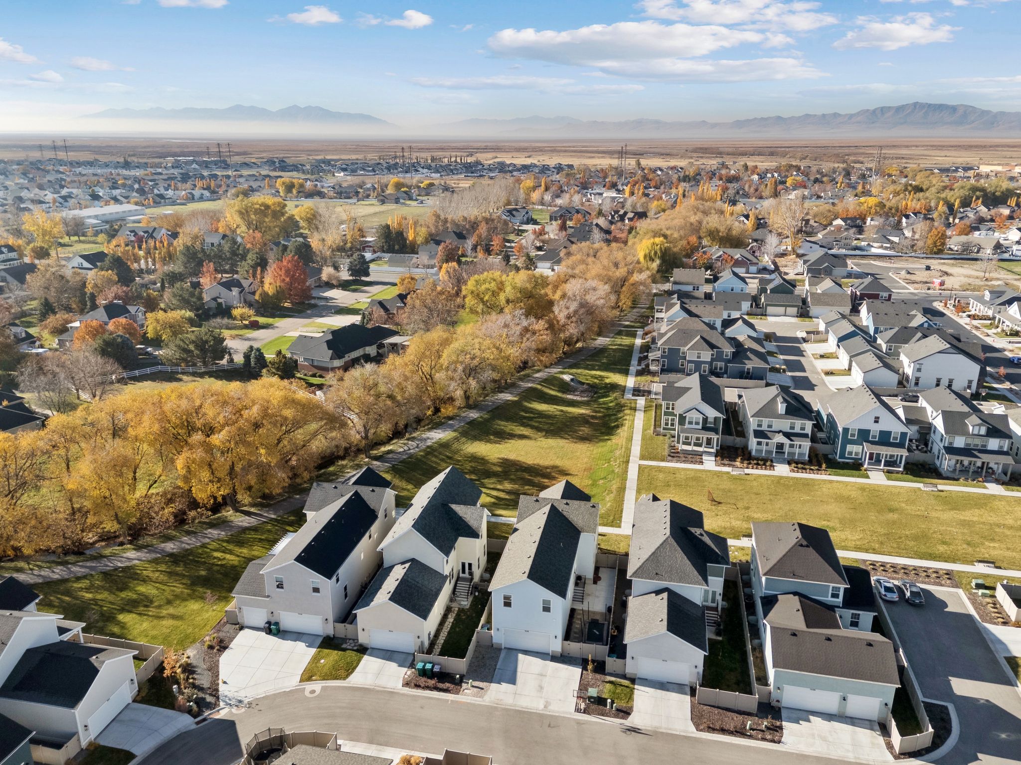 Newly constructed residential community featuring contemporary homes with dark shingle roofs, light-colored siding, and attached garages