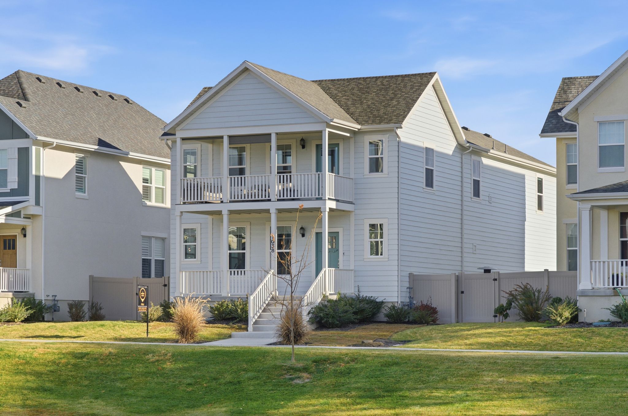 Two-story property featuring light-colored siding, a covered porch, and an upper-level balcony