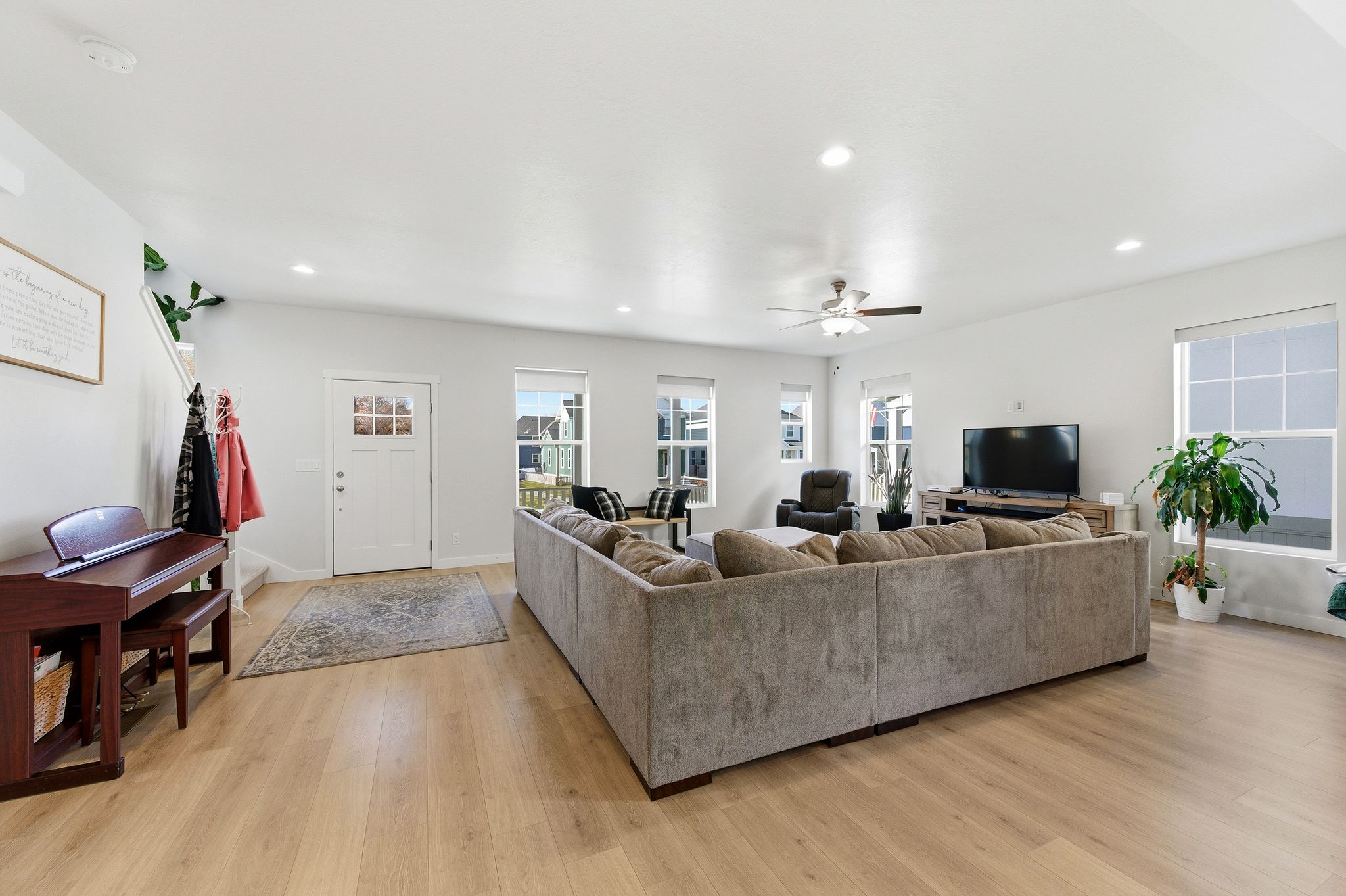 Spacious living area featuring light wood-finish flooring, recessed lighting, and multiple windows