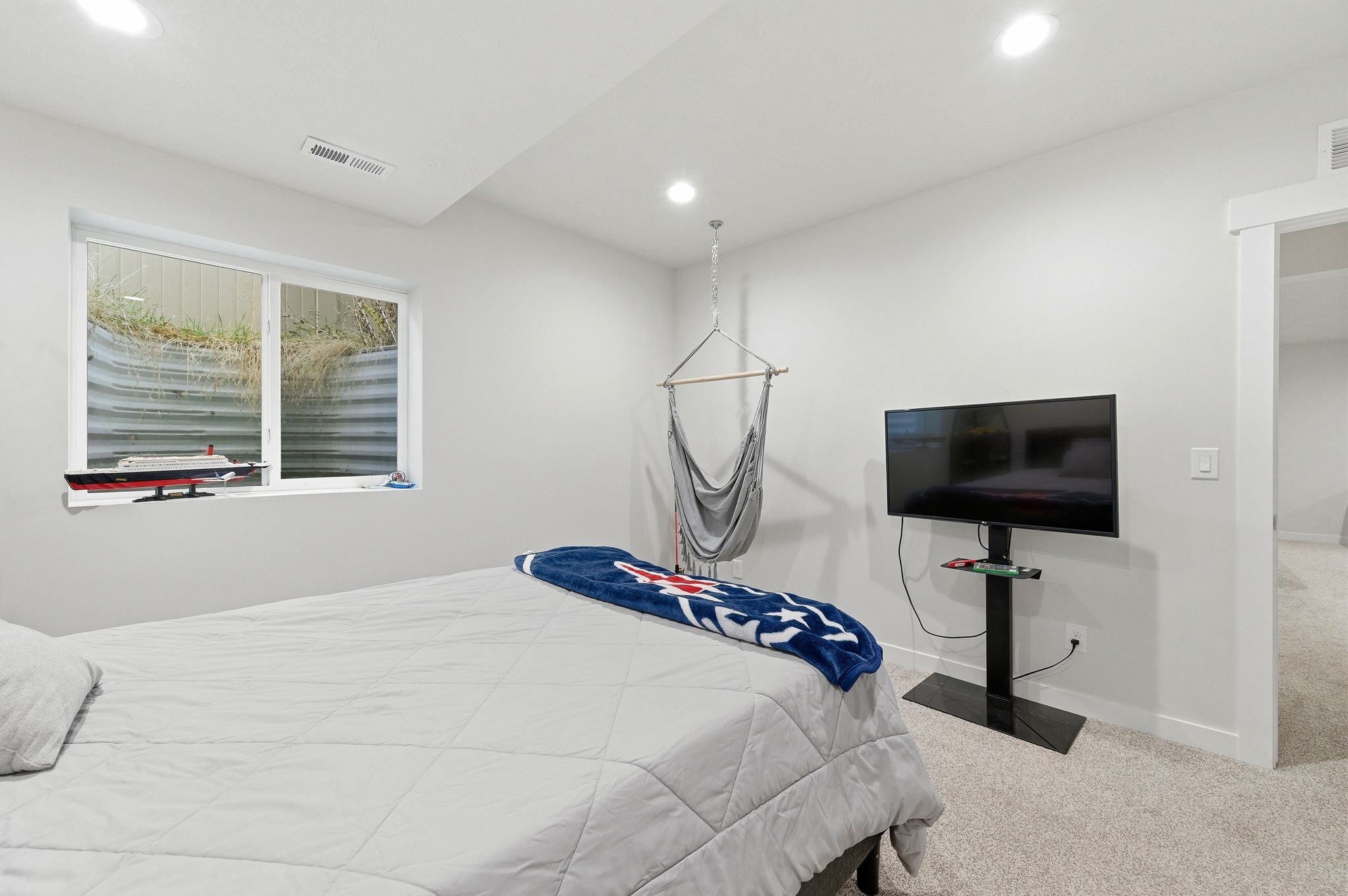 Carpeted room featuring a large window with a window well, recessed lighting, white walls, and a built-in wall niche