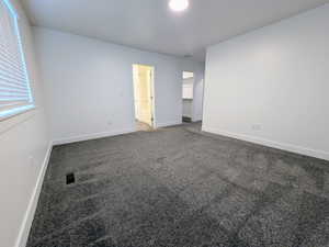 Spacious room featuring gray textured carpeting, white walls, and bright overhead lighting