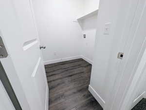 Dedicated laundry area featuring wood-finish flooring, crisp white walls, and a built-in shelf
