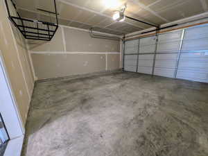 Spacious garage featuring a concrete floor, overhead storage rack, automatic garage door opener, and recessed ceiling lighting