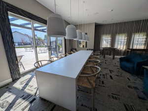 Spacious community room featuring a large central table, modern pendant lighting, and patterned carpeting