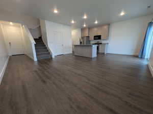 Open-concept living area featuring wood-finish flooring, recessed lighting, and a modern kitchen with a central island