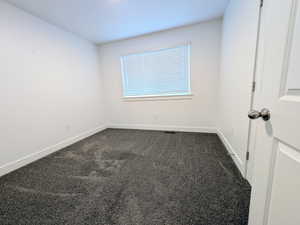 Room featuring dark gray carpeting, crisp white walls, and a window with blinds
