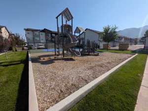 Outdoor playground area featuring a multi-level play structure with slides and climbing elements set on wood chip surfacing