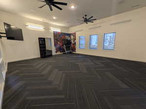 Spacious room featuring patterned carpet flooring, recessed lighting, and two ceiling fans