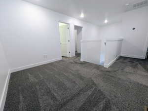 Upper-level loft area featuring dark gray carpet, white baseboards, and bright white walls