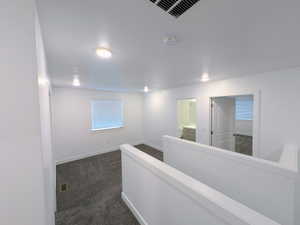 Upper level landing featuring neutral carpeting, white balustrade, recessed ceiling lighting, and crisp white walls