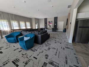 Spacious common area featuring patterned carpet flooring, recessed lighting, a built-in refrigerator, and full-height window treatments