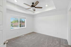 Recessed lighting illuminates a tray ceiling with a ceiling fan