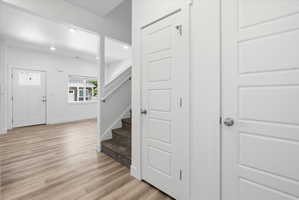 Entryway featuring light wood-finish flooring, white paneled doors, recessed lighting, and a window with white trim