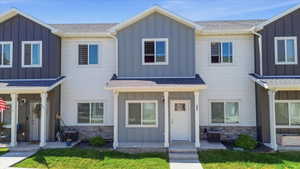Townhome exterior featuring a contrasting color palette, board and batten siding, horizontal siding, stone veneer accents, and a covered entry