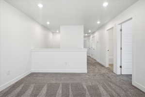 Carpeted loft area featuring recessed lighting