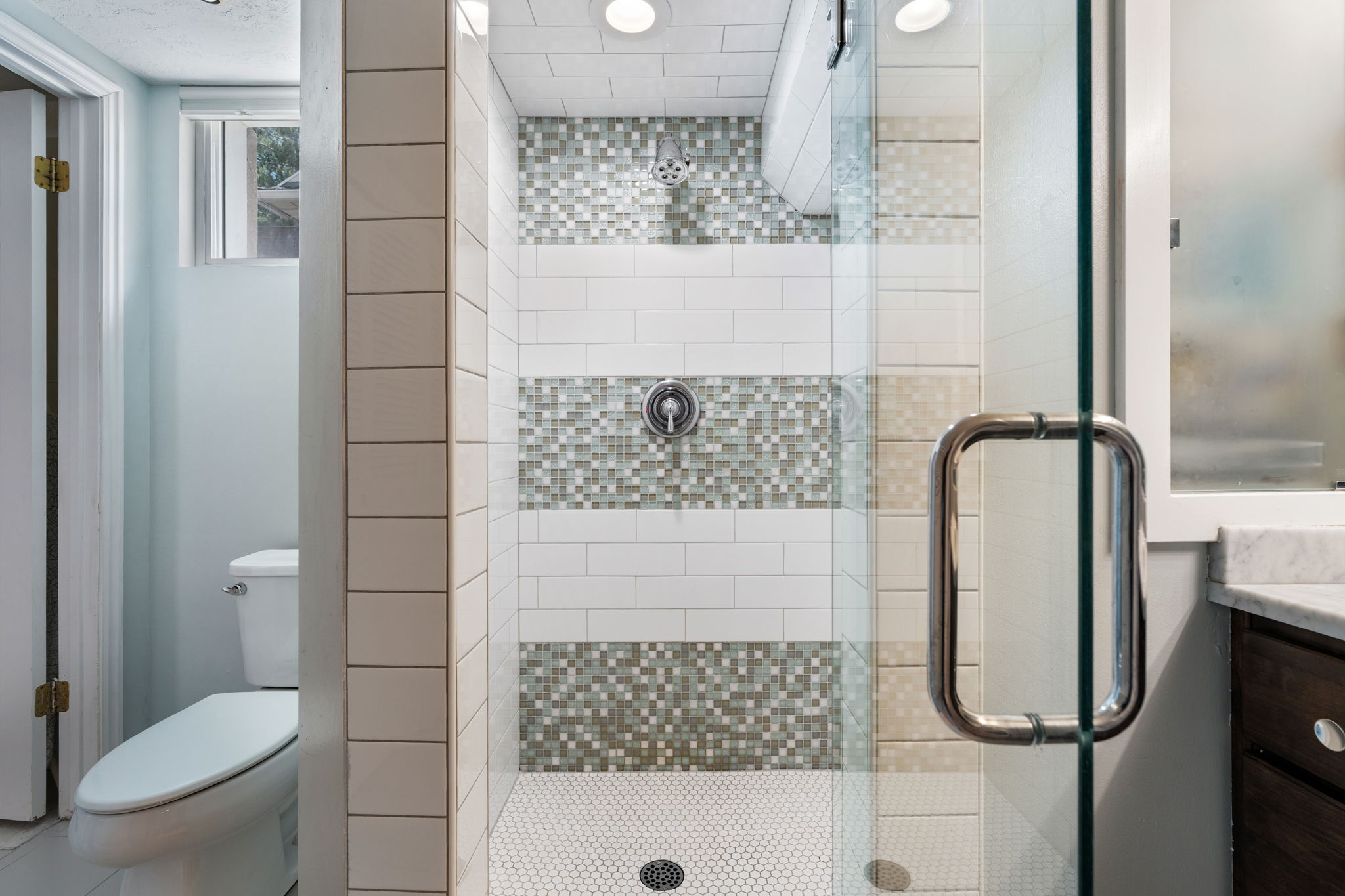 Modern shower enclosure featuring clear glass panels and a chrome handle