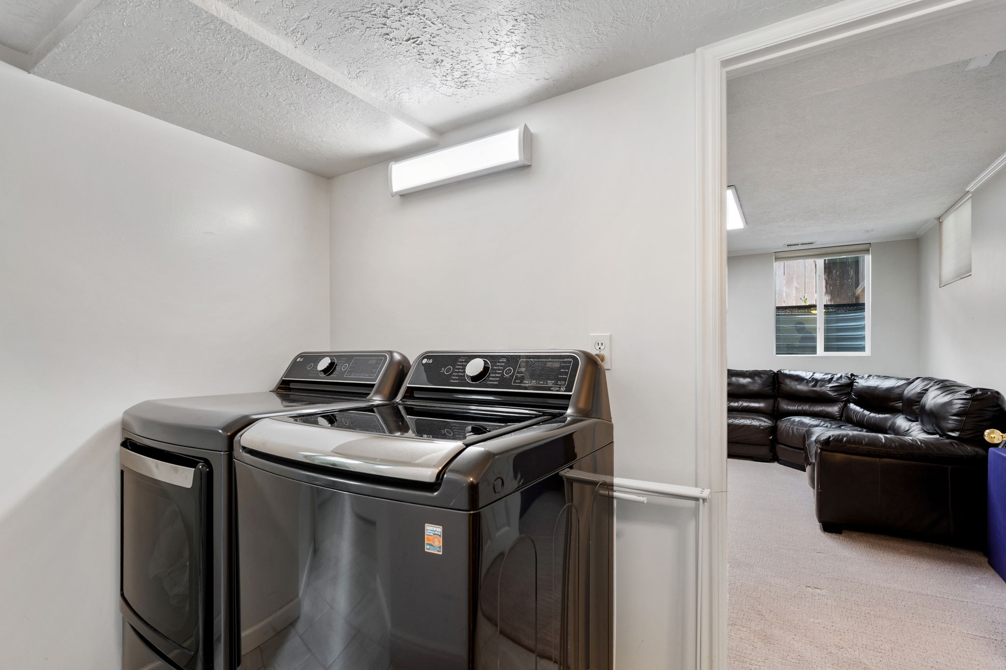 Dedicated laundry area with light gray walls and a textured ceiling