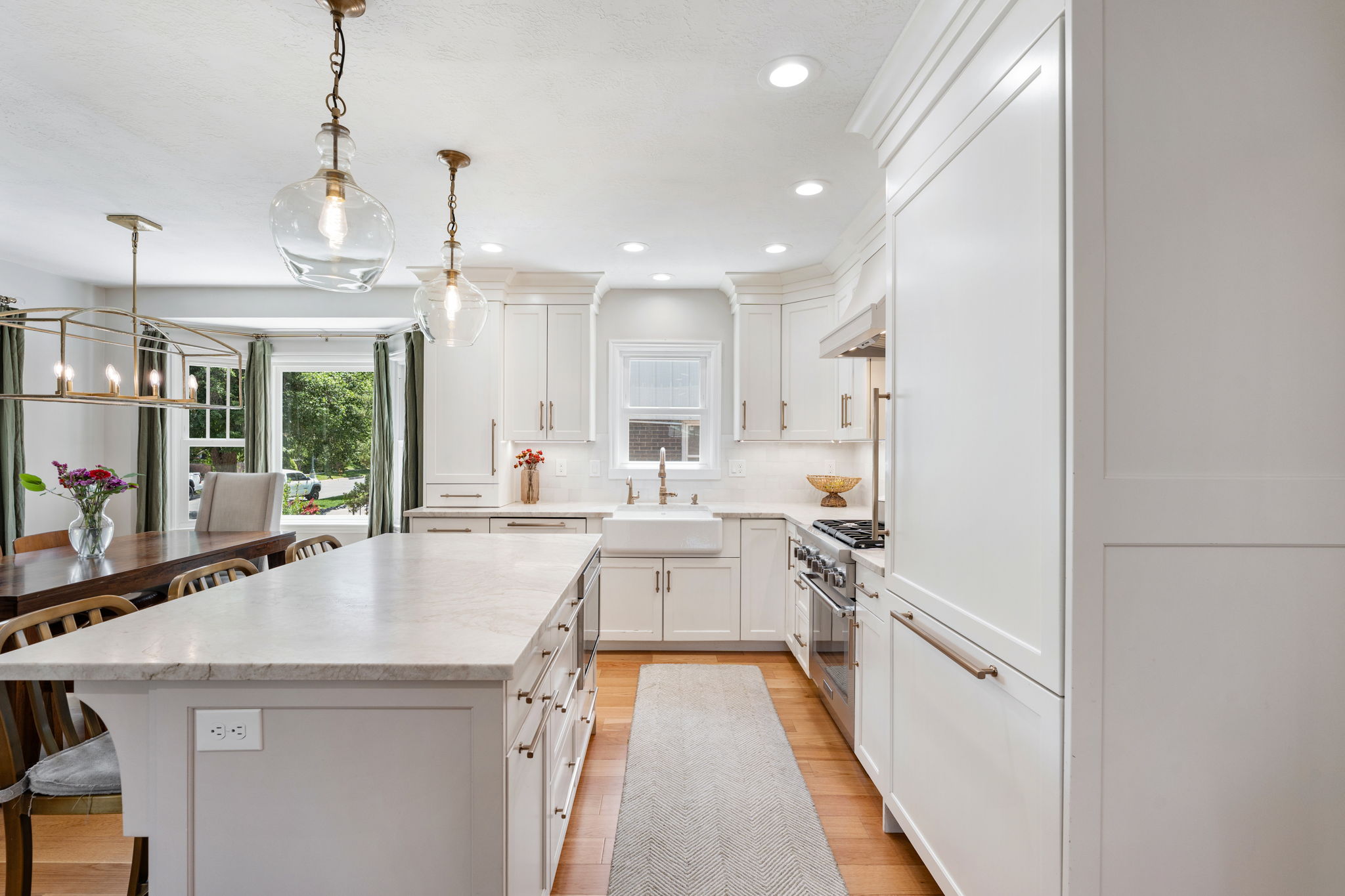 Bright kitchen featuring white cabinetry, a large center island with a light-toned countertop, stainless steel appliances, and recessed lighting