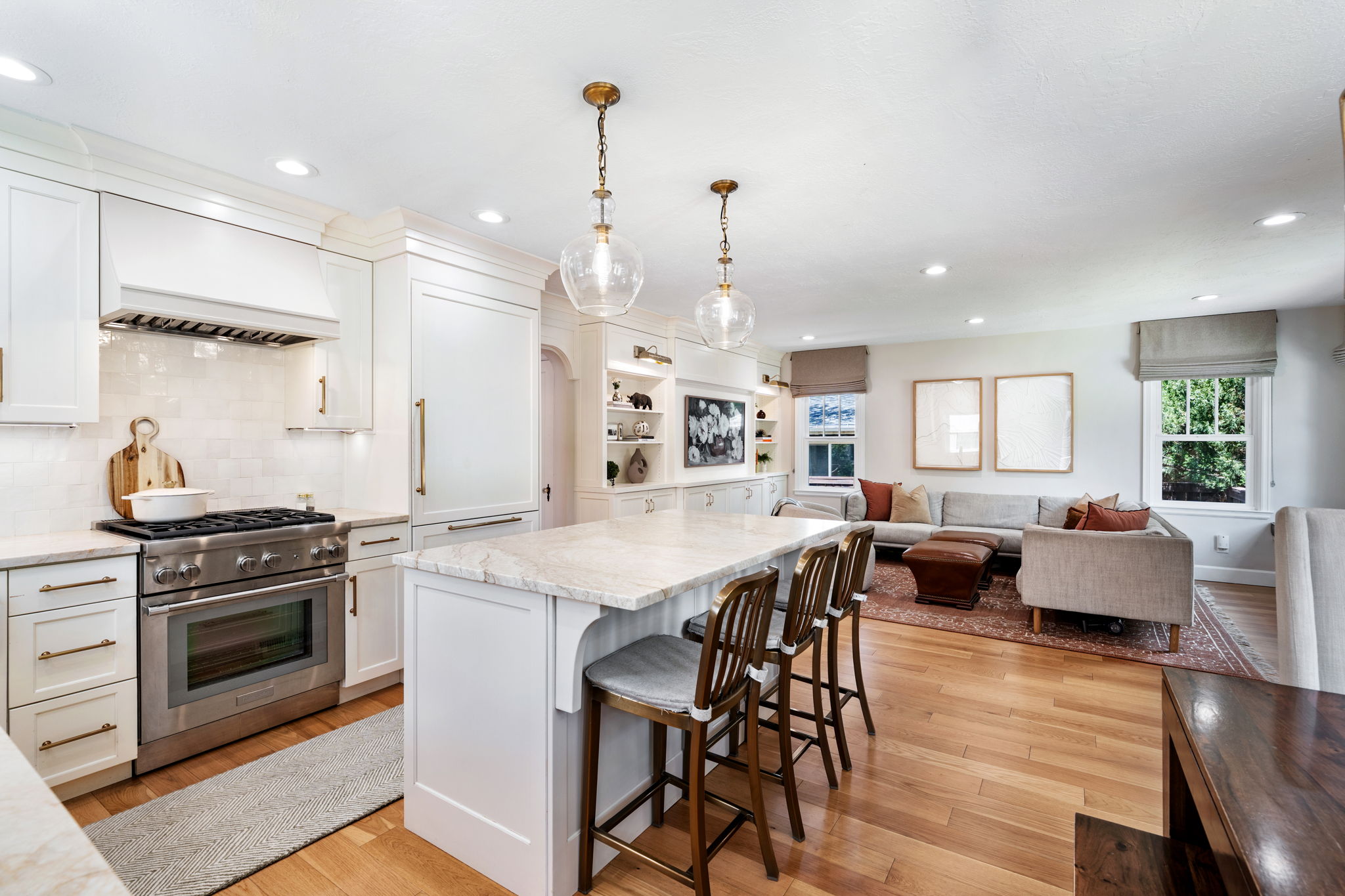 Bright kitchen featuring white cabinetry, stainless steel range with hood, stone countertops, and a subway tile backsplash