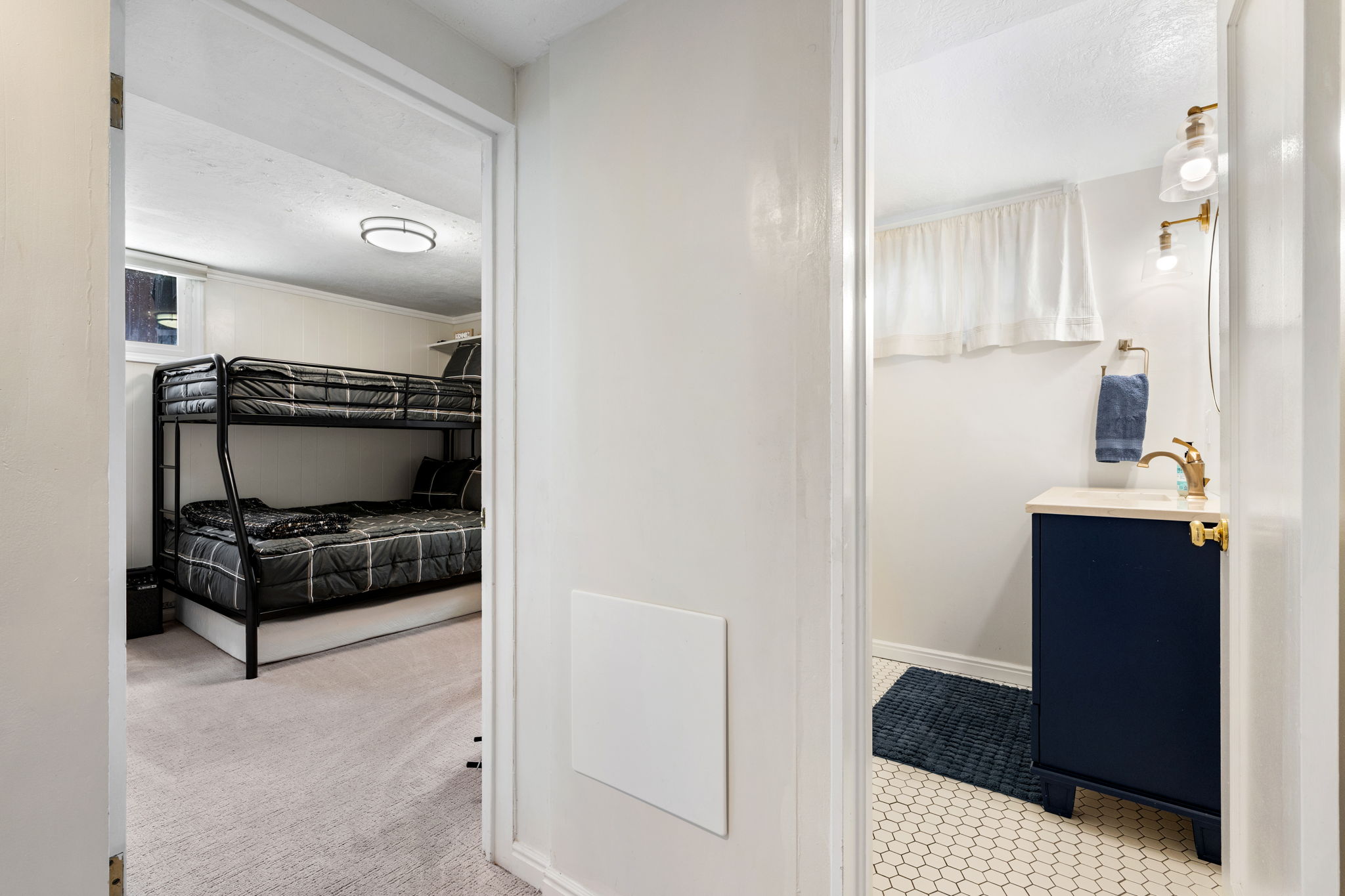 Interior bathroom featuring a navy vanity with a countertop, brass-finish faucet, and coordinating wall-mounted light fixtures