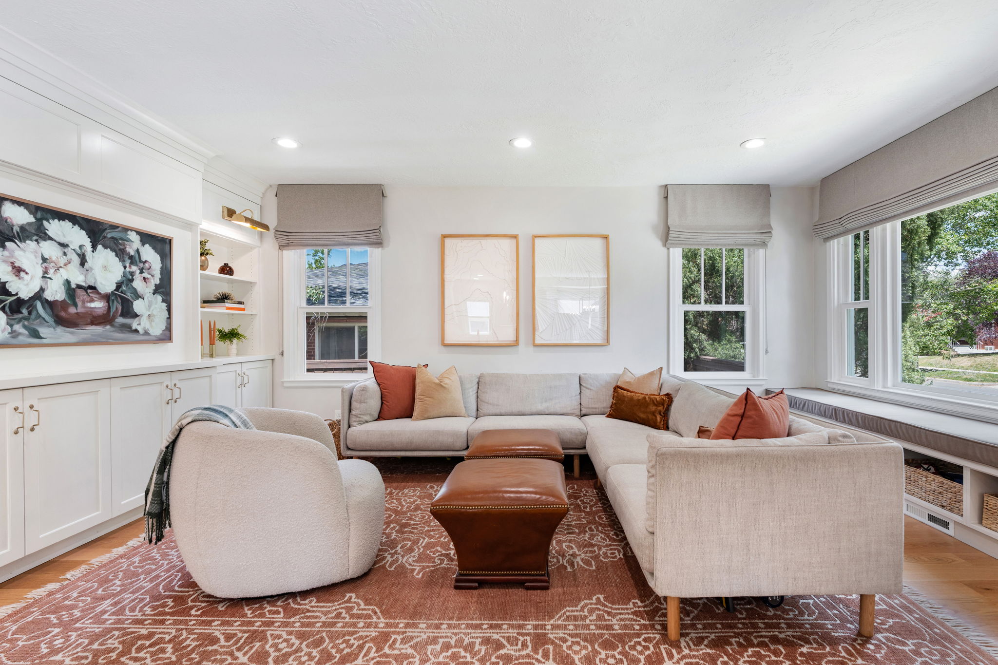 Spacious living area featuring extensive built-in white cabinetry, integrated shelving, wood-finish flooring, recessed lighting, and a window seat with storage