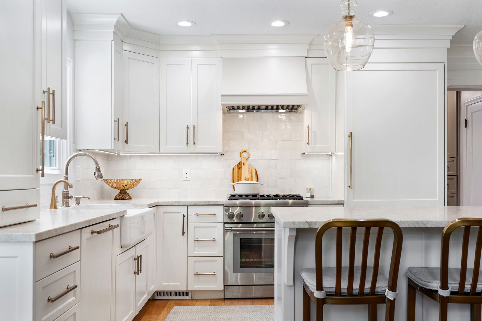 Gourmet kitchen with white cabinetry, stone countertops, farmhouse sink, stainless steel range, and tile backsplash