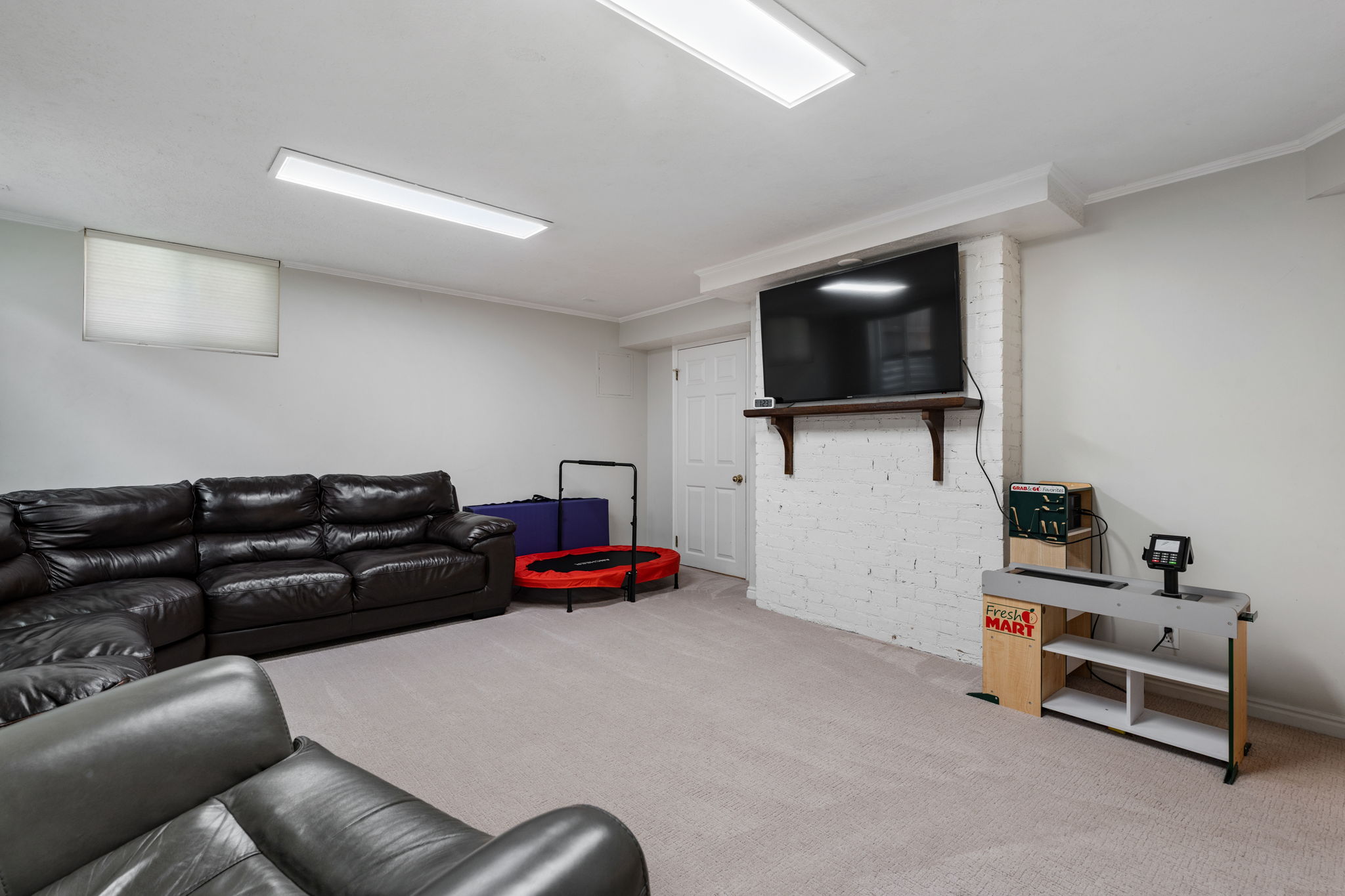 Spacious carpeted room featuring a white painted brick accent wall, built-in shelving, and recessed lighting