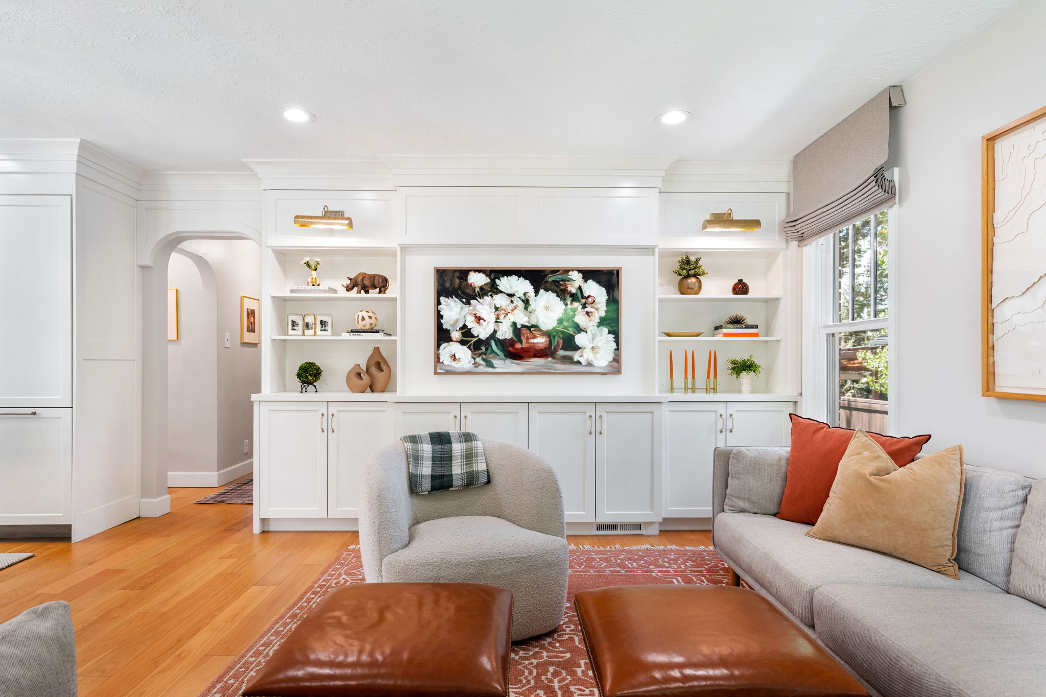 Bright living space featuring extensive built-in cabinetry with shelving, recessed lighting, and wood-finish flooring