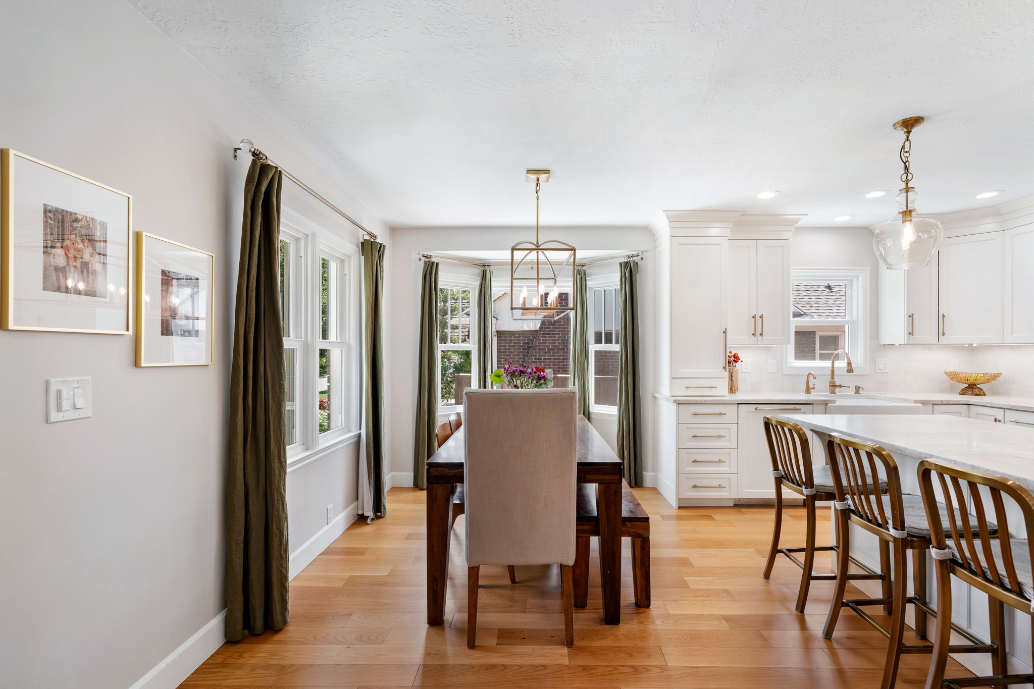 Dining area featuring wood-finish flooring, a bay window, and a linear chandelier