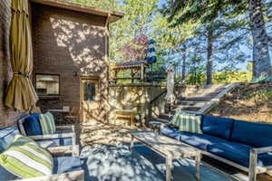 Tiered backyard featuring a brick exterior, concrete patio, built-in wooden stairs, and established trees