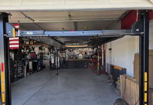 Spacious garage featuring a four-post vehicle lift, concrete flooring, and built-in shelving -