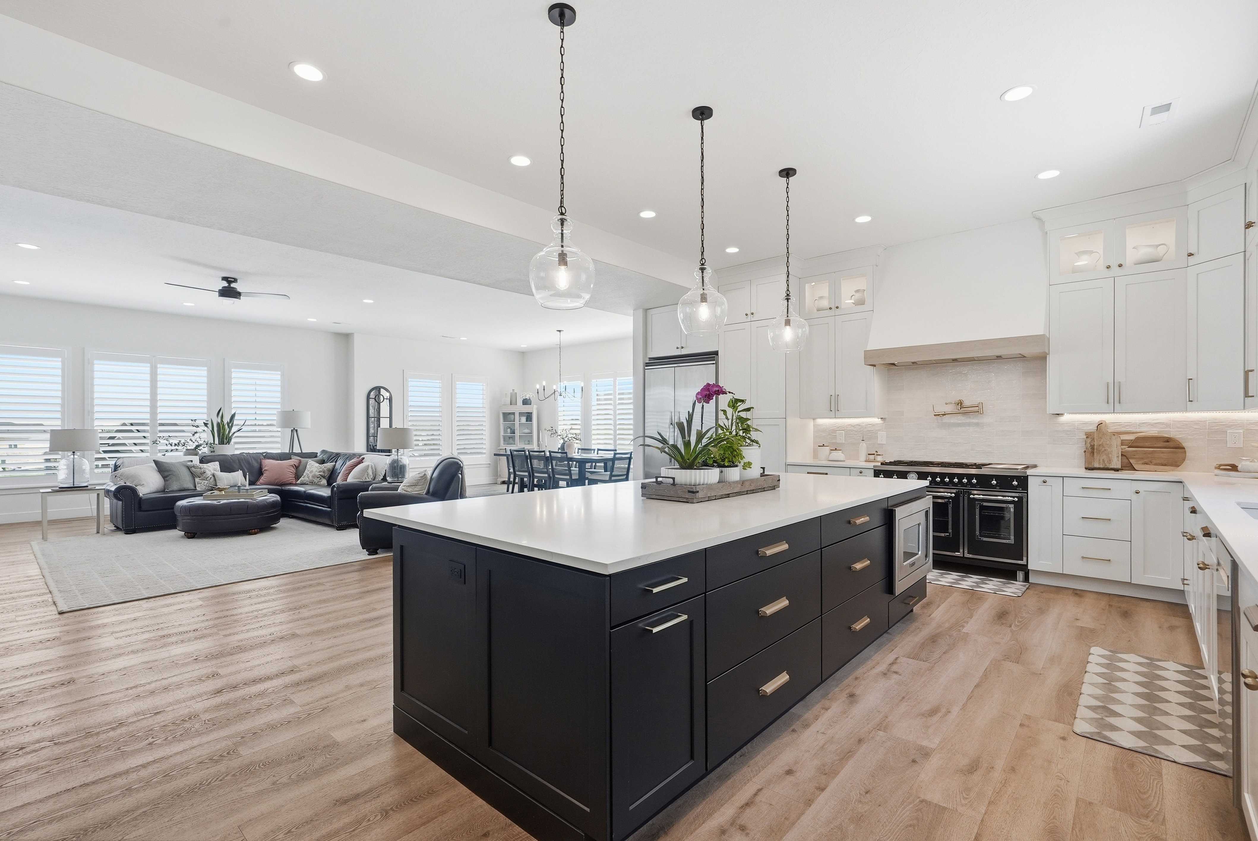 Spacious open-concept living area featuring a large kitchen island with integrated microwave, LVP flooring, recessed lighting, and white cabinetry