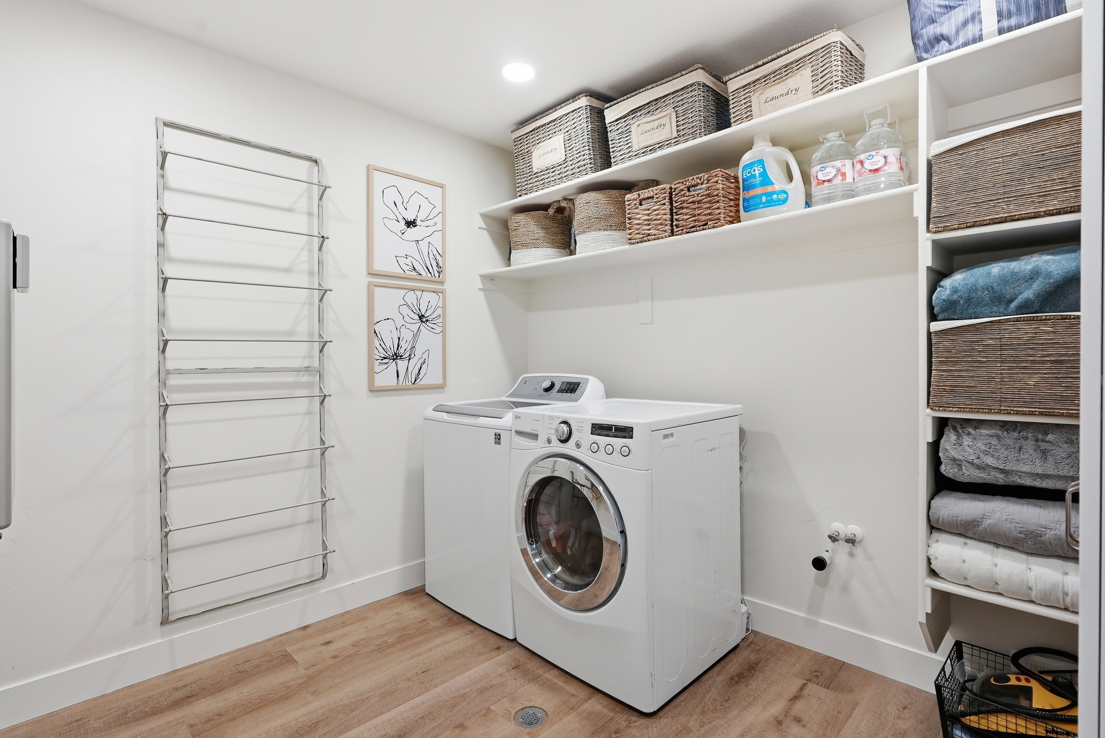 Dedicated laundry area featuring wood-finish flooring, white walls, and bright overhead lighting