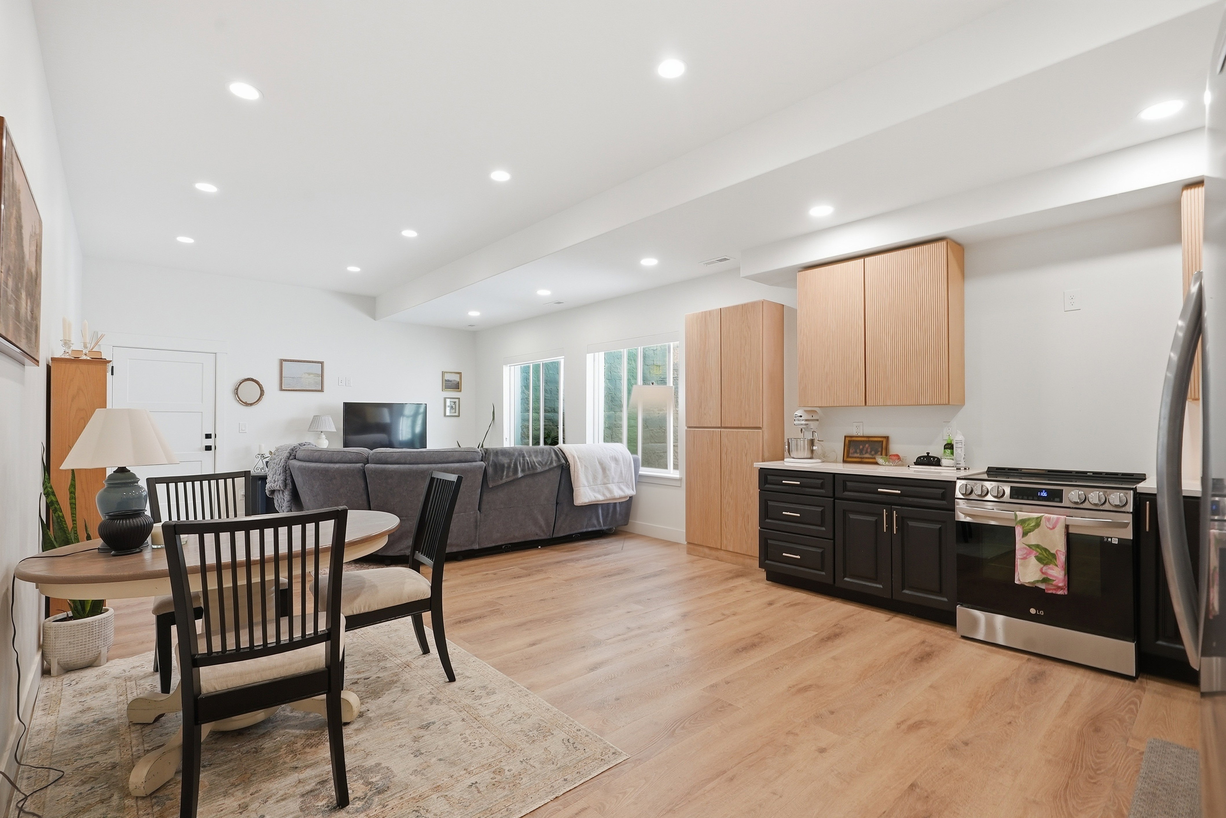 Open-concept living area featuring LVP flooring, recessed lighting, and white walls