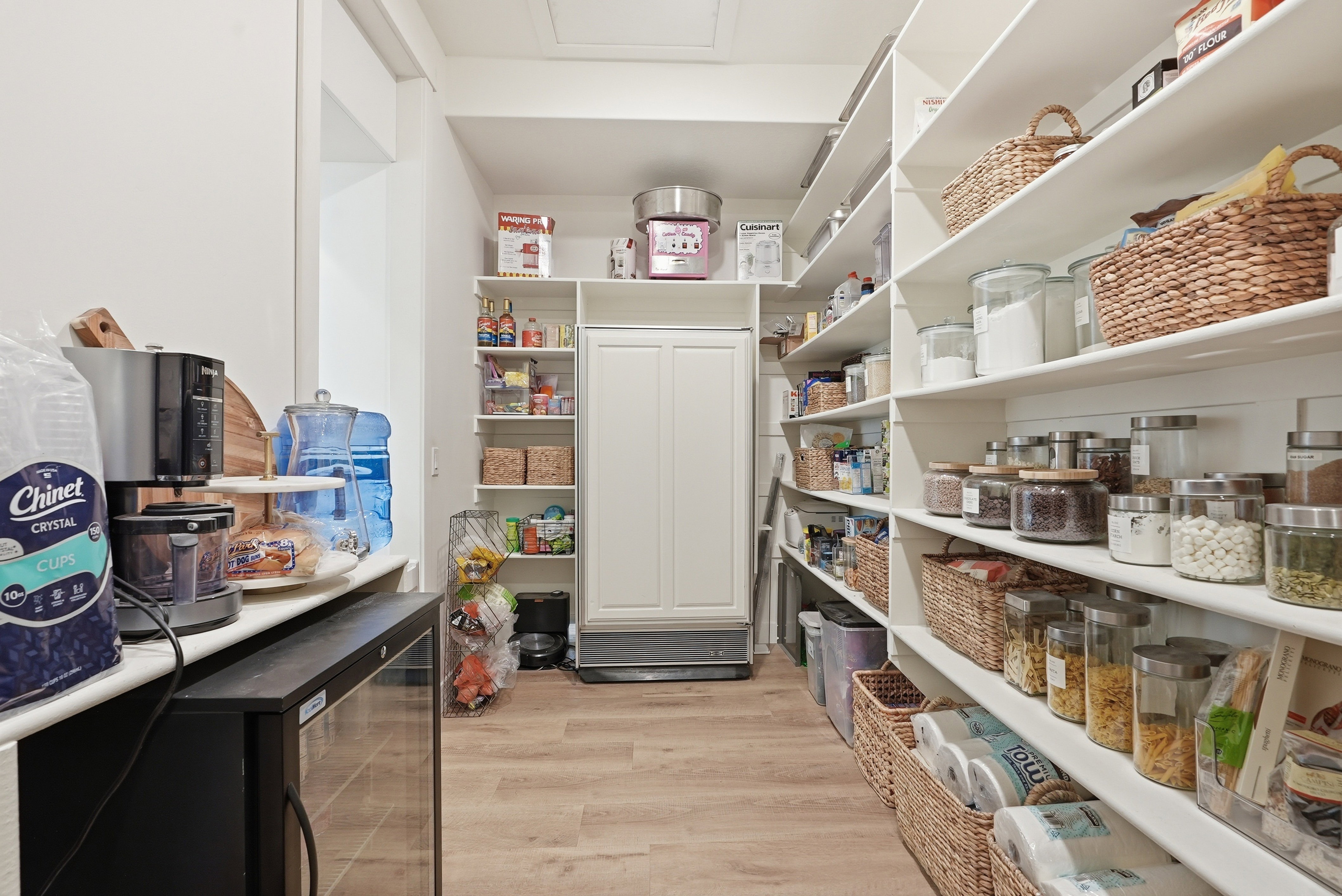 Spacious pantry with extensive built-in shelving, LVP flooring, a beverage cooler, and a built-in upright freezer