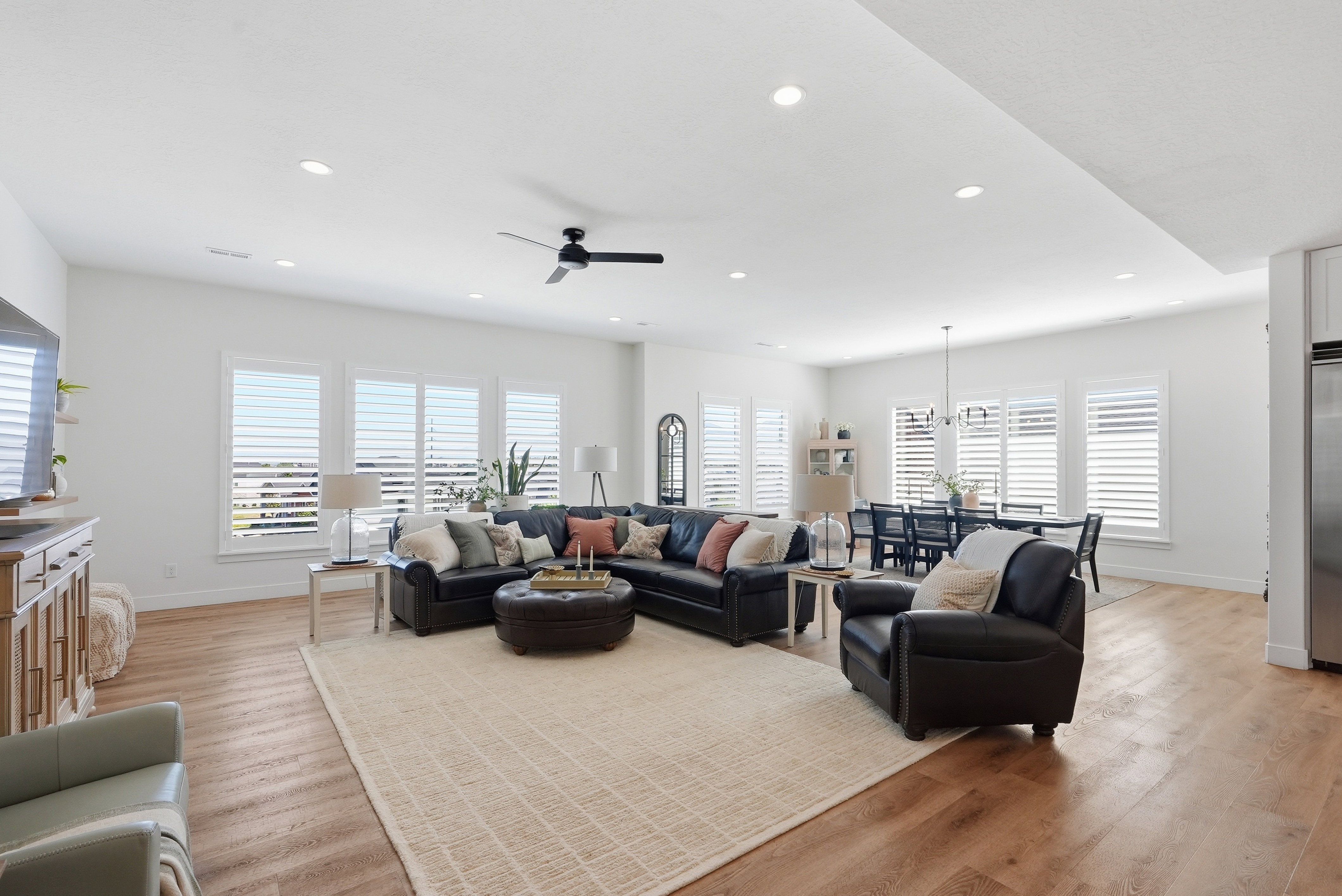 Open-concept living area featuring LVP flooring, recessed lighting, and multiple windows with plantation shutters