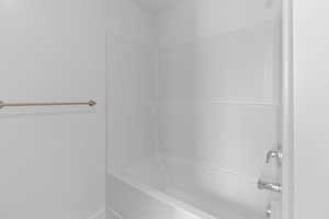 White bathtub with integrated shower surround and chrome fixtures