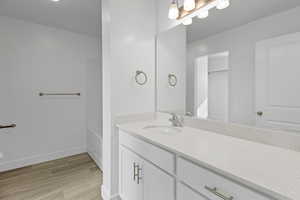 Bathroom featuring a white vanity with a speckled countertop, a large mirror, and a chrome faucet