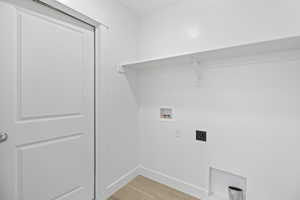Dedicated utility space featuring a built-in shelving unit, white baseboards, and wood-finish flooring