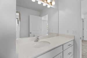 Bathroom vanity featuring a speckled countertop, undermount sink, and chrome faucet