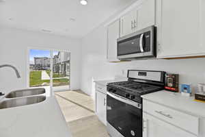 Modern kitchen featuring white cabinetry, light-colored countertops, and wood-finish flooring