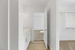 Hallway vanity with a light-toned countertop, white cabinetry with silver-tone hardware, and wood-finish flooring