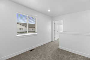 Carpeted interior space with a window featuring horizontal blinds