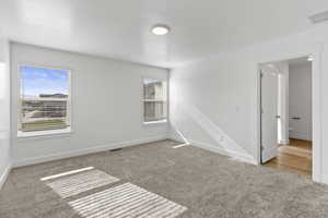 Bright room featuring neutral-toned carpet, two windows with blinds, a flush mount ceiling light, and white trim throughout