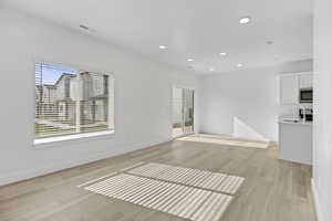 Open-concept living area featuring light wood-finish flooring, white walls, and recessed lighting