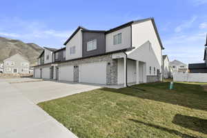 Contemporary townhome exterior featuring white siding, dark gray accents, and stone veneer detailing