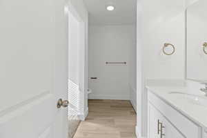 Bathroom vanity featuring a white countertop with integrated sink, brushed brass hardware, and a large mirror